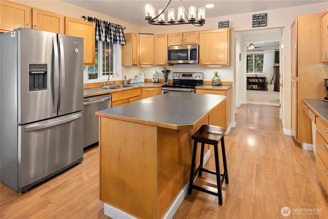 a kitchen with stainless steel appliances a refrigerator a stove a sink dishwasher and a microwave oven on the wooden floor