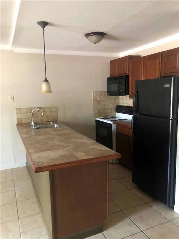 7007 Guadalupe Street, Unit 1 Austin, TX 78752 - Photo 2 of 8 Kitchen featuring a peninsula, black appliances, backsplash, light tile patterned floors, and tile countertops