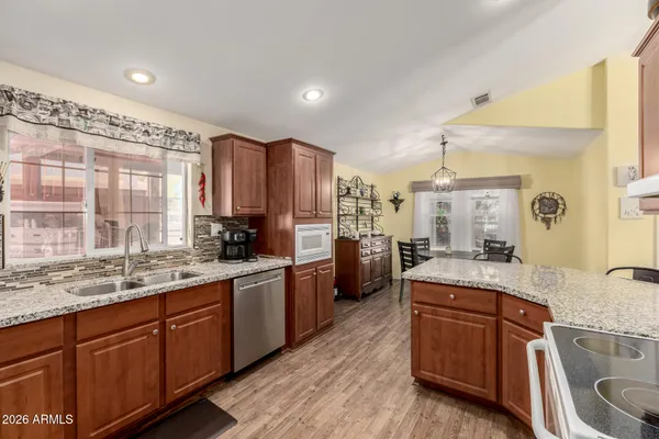 a kitchen with stainless steel appliances granite countertop wooden cabinets a sink a stove a dining table and chairs