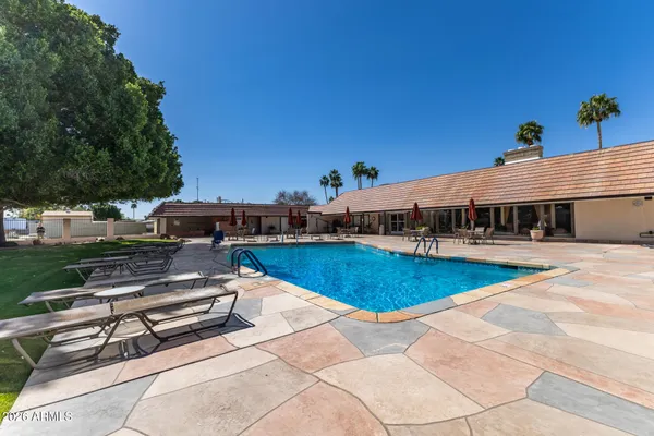 a view of a patio with dining table and chairs under an umbrella with potted plants