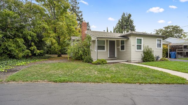 a view of a house with a yard and large tree