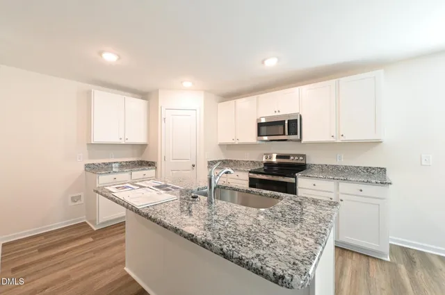 a kitchen with stainless steel appliances granite countertop a sink stove and cabinets