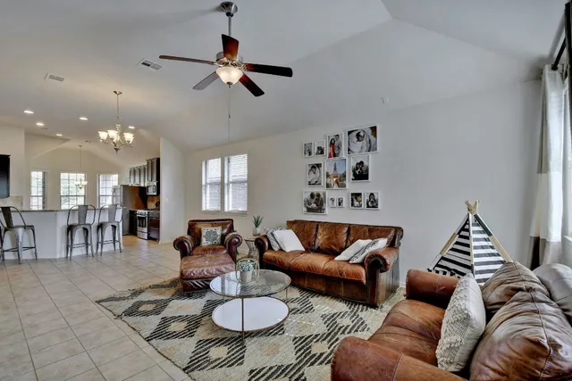 a living room with furniture kitchen view and a chandelier