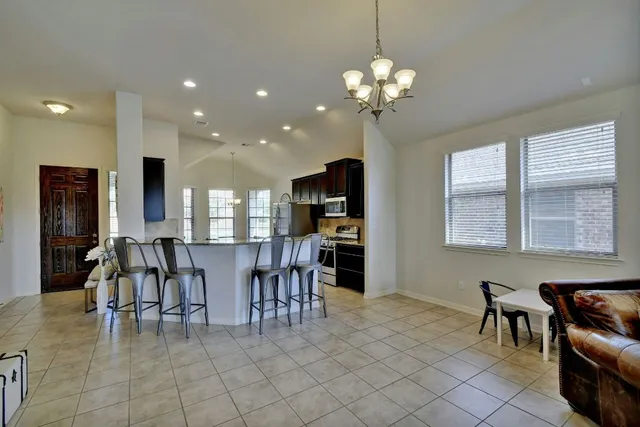 a dining room with furniture a chandelier and kitchen view