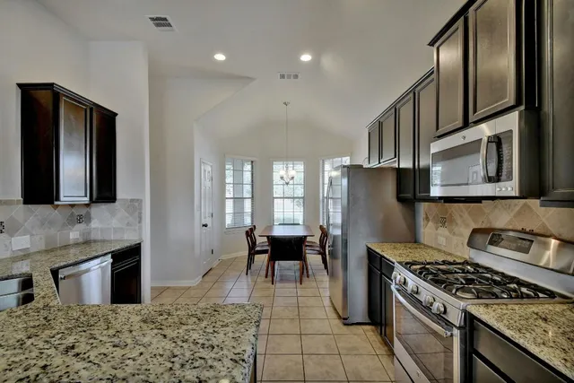a kitchen with stainless steel appliances granite countertop a sink stove and refrigerator