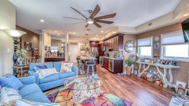 a living room with furniture kitchen view and a wooden floor