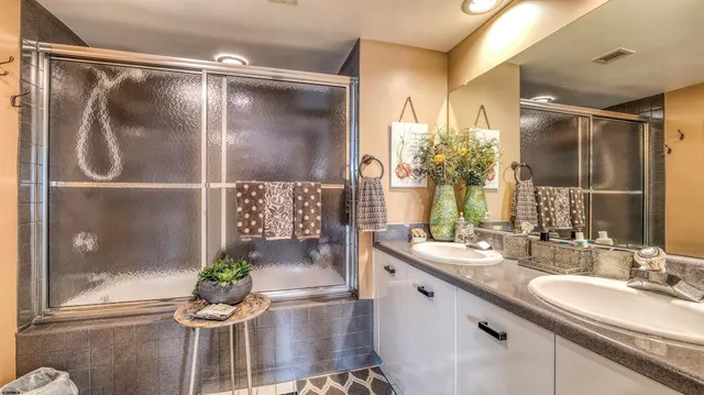 a bathroom with a granite countertop sink a mirror and a shower