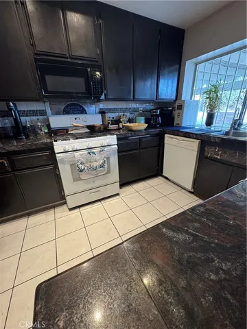 a kitchen with stainless steel appliances kitchen island granite countertop a stove a refrigerator a sink and a cabinets