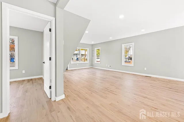 a view of a livingroom with a kitchen space and wooden floor