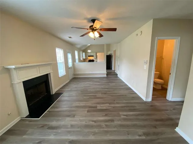 a view of a livingroom with a fireplace a ceiling fan and hardwood floor