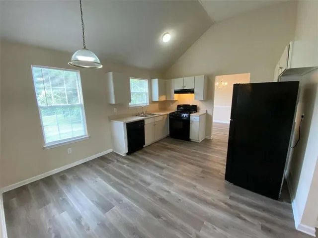 a kitchen with stainless steel appliances granite countertop a refrigerator a sink dishwasher a stove and white countertops with wooden floor