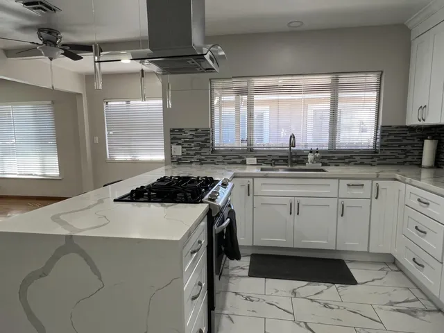 a kitchen with a stove a sink a window and cabinets
