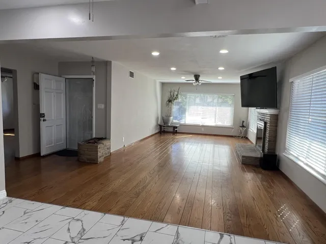 an empty room with wooden floor a fireplace and windows