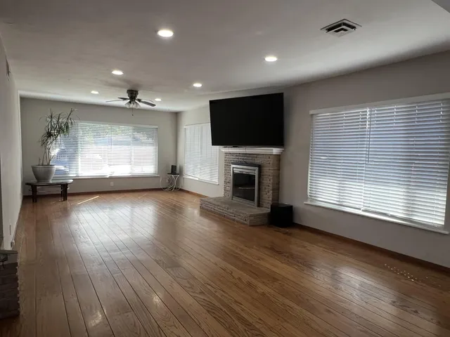 an empty room with fireplace wooden floor and windows