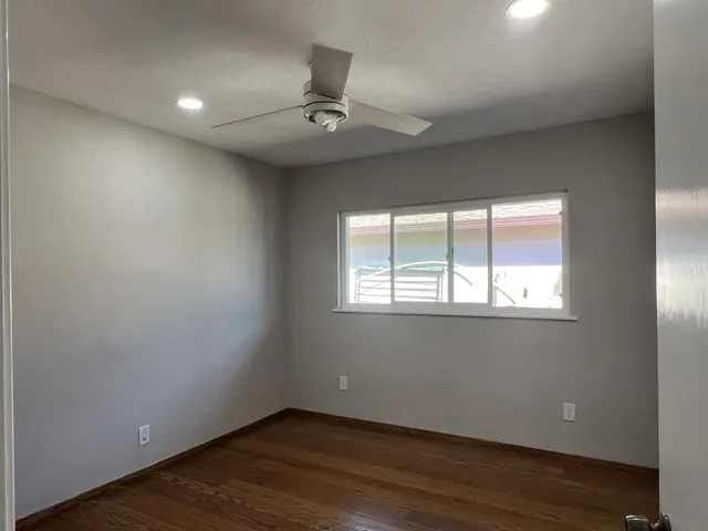 an empty room with wooden floor and windows