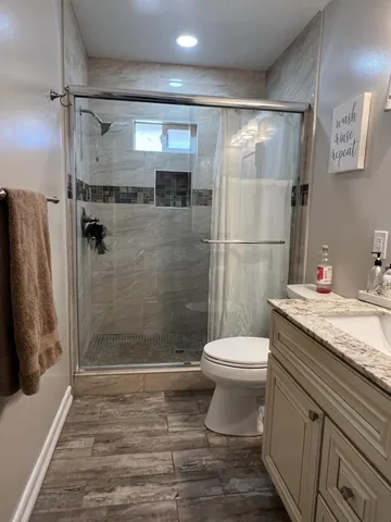 a bathroom with a granite countertop sink toilet and shower