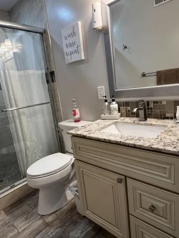 a bathroom with a granite countertop toilet sink and mirror