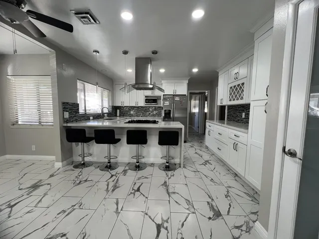 a kitchen with stainless steel appliances a refrigerator a stove a sink dishwasher a dining table and chairs with wooden floor