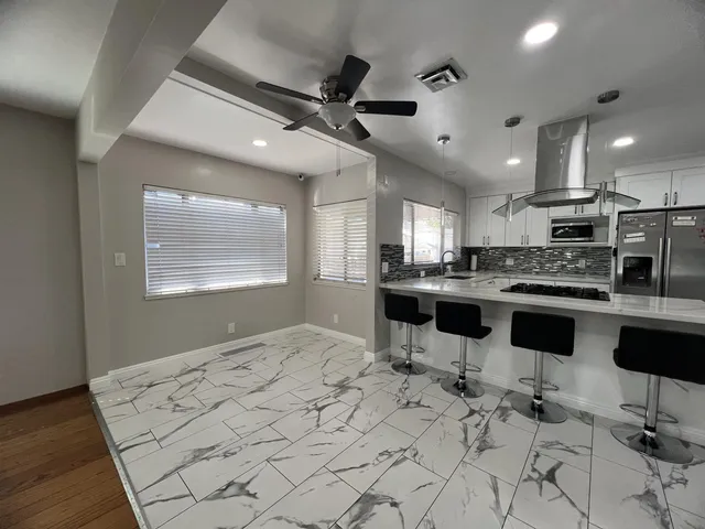 a kitchen with stainless steel appliances kitchen island granite countertop a stove a sink a dining table and chairs