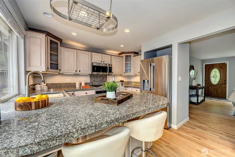 a kitchen with stainless steel appliances granite countertop a sink refrigerator and cabinets