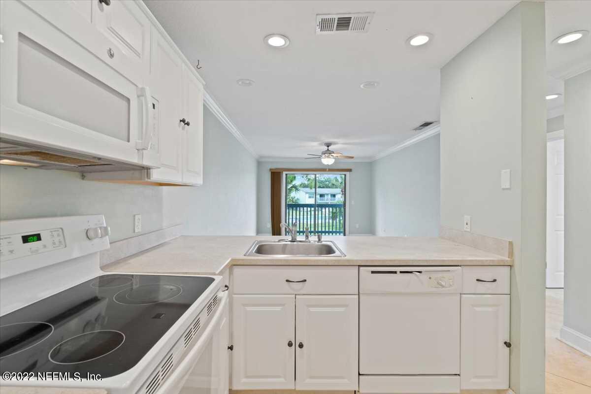 700 West Pope Road, Unit C20 St. Augustine, FL 32080 - Photo 6 of 15 a kitchen with granite countertop a sink dishwasher and white cabinets with wooden floor