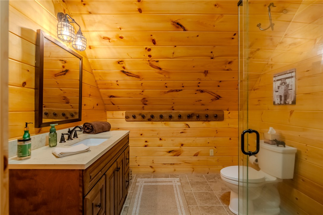 102 State Rd S-39-143 Sunset, SC 29685 - Photo 44 of 47 This cozy bath features warm wood walls, a vanity with a sleek countertop, and a glass-enclosed shower.