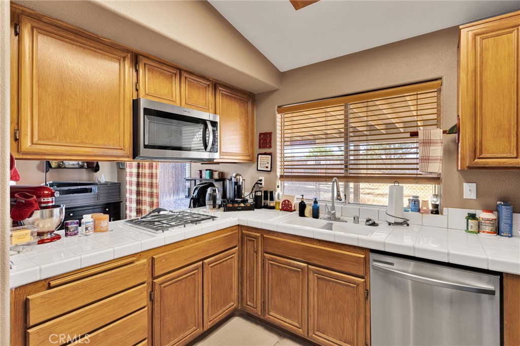 20403 Ochoa Road Apple Valley, CA 92307 - Photo 22 of 48 a kitchen with stainless steel appliances wooden cabinets a sink and a window