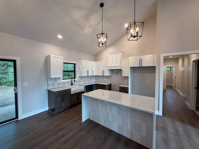 a large kitchen with stainless steel appliances granite countertop a refrigerator a sink dishwasher a dining table and chairs with wooden floor