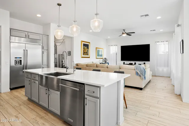 a large kitchen with stainless steel appliances a stove center island with wooden floor and chandelier