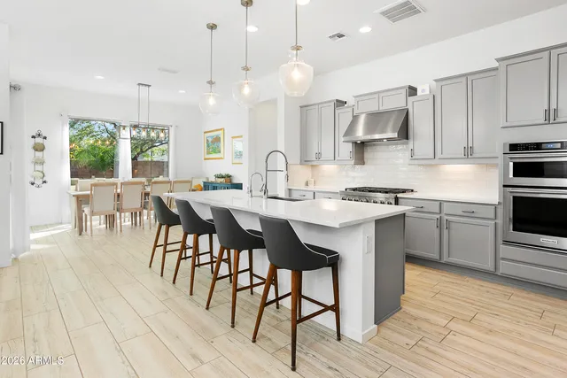 a kitchen with stainless steel appliances granite countertop a stove a sink dishwasher a dining table and chairs with wooden floor