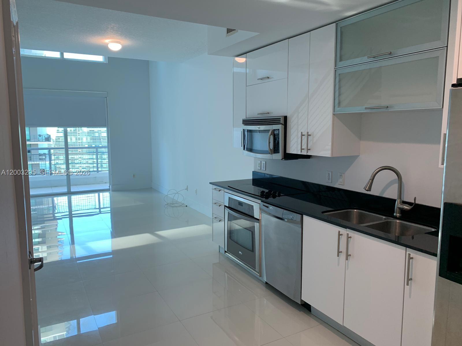 60 Southwest 13th Street, Unit 3202 Miami, FL 33130 - Photo 2 of 13 a kitchen with granite countertop a sink and a stove top oven