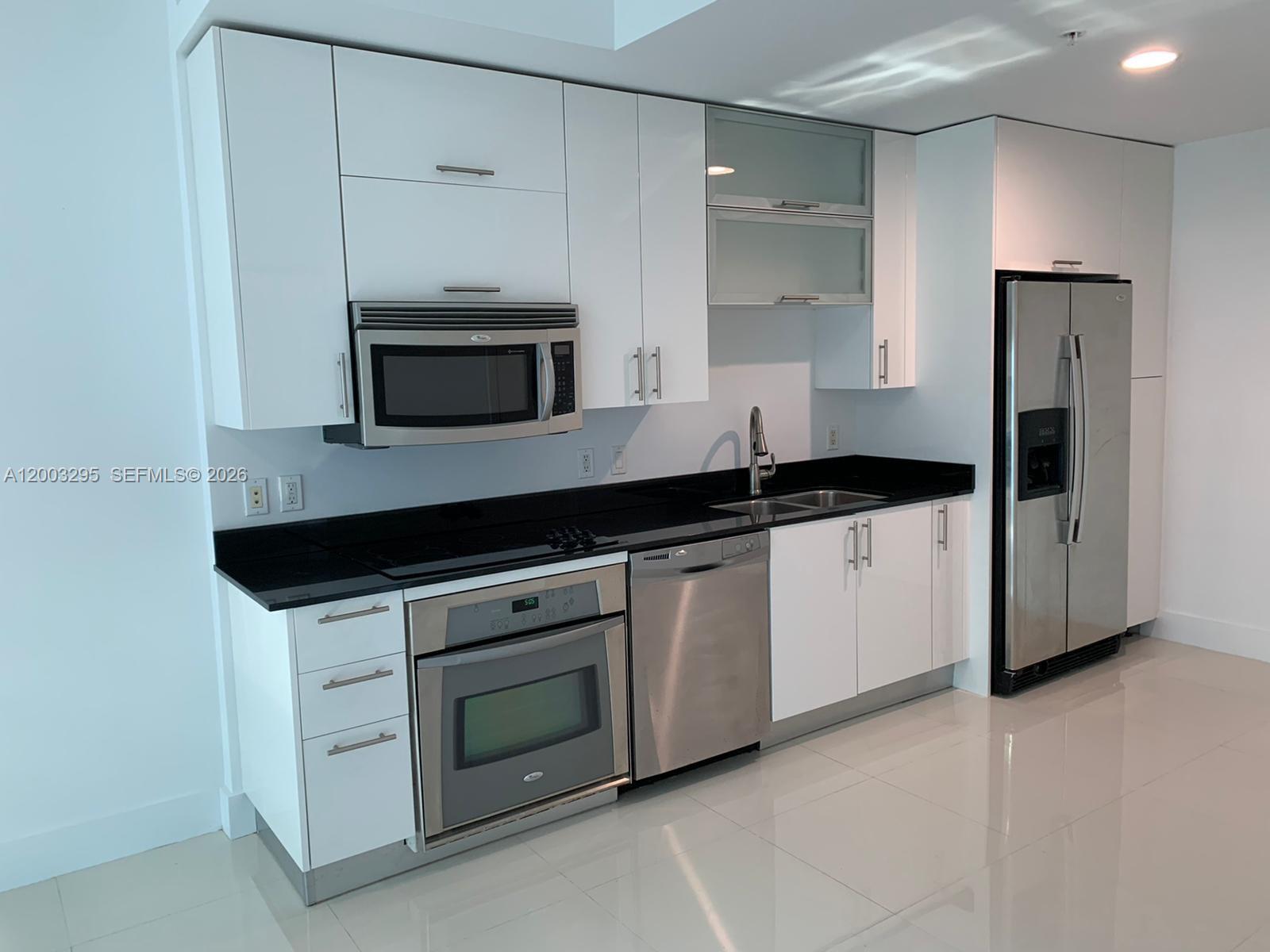 60 Southwest 13th Street, Unit 3202 Miami, FL 33130 - Photo 4 of 13 a kitchen with granite countertop white cabinets and stainless steel appliances