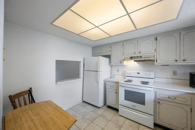 an empty room with a chandelier fan and windows