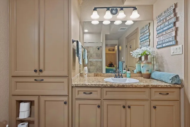 a bathroom with a granite countertop sink a mirror and a shower