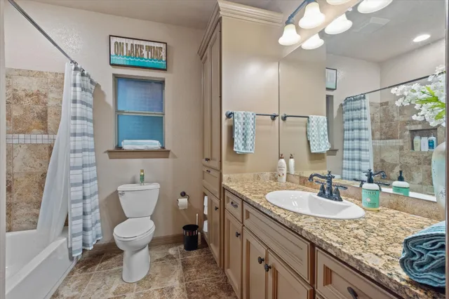 a bathroom with a granite countertop sink mirror vanity and toilet