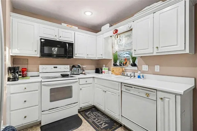 a kitchen with granite countertop white cabinets white stainless steel appliances and sink