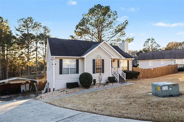 a view of a white house with a yard and sitting area