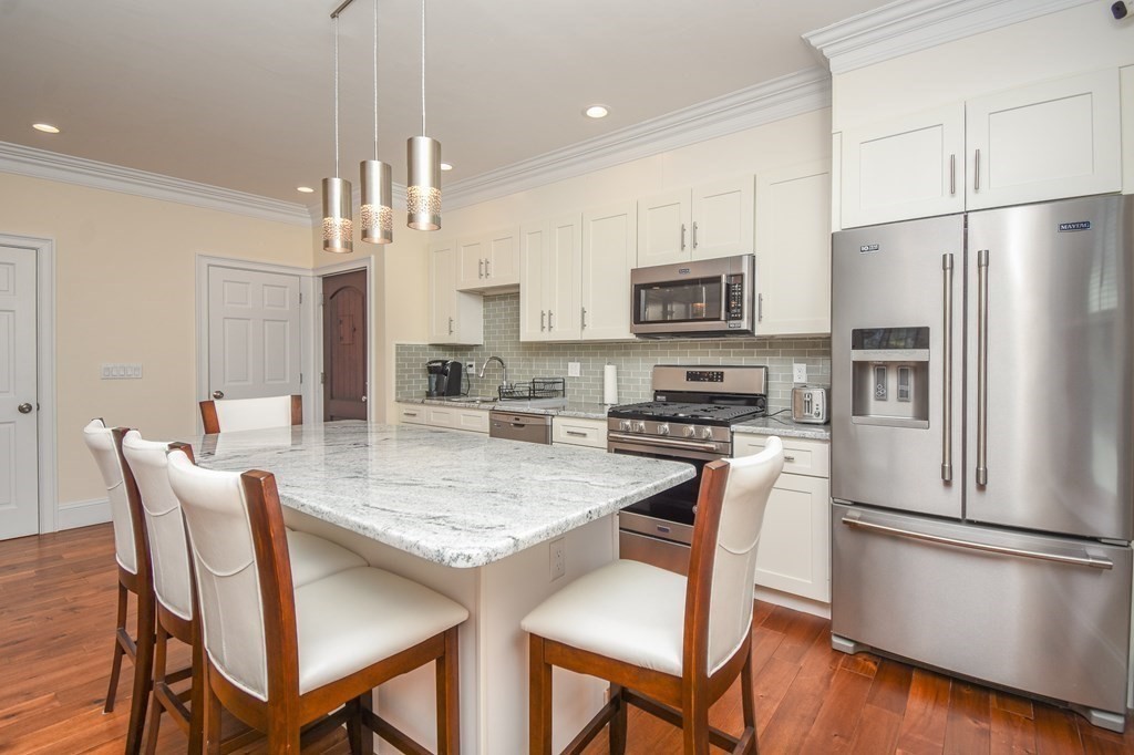 32 Cameron Street Everett, MA 02149 - Photo 2 of 22 a kitchen with stainless steel appliances granite countertop a dining table chairs refrigerator and microwave