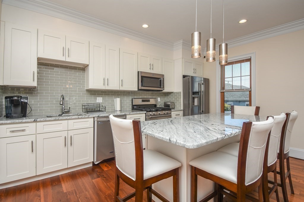 32 Cameron Street Everett, MA 02149 - Photo 4 of 22 a kitchen with stainless steel appliances granite countertop a stove top oven a refrigerator a sink and a dining table with white cabinets