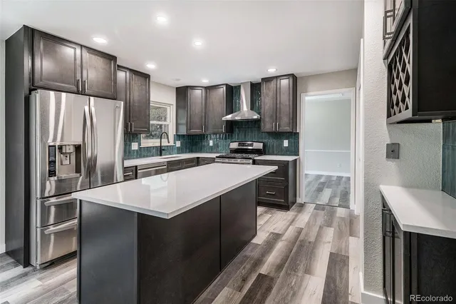 a kitchen with stainless steel appliances granite countertop a refrigerator a stove and a sink with wooden floor