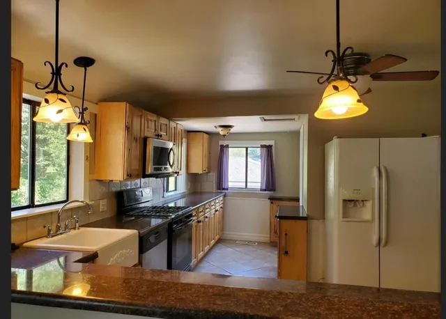 a kitchen with stainless steel appliances granite countertop a sink a stove and a refrigerator