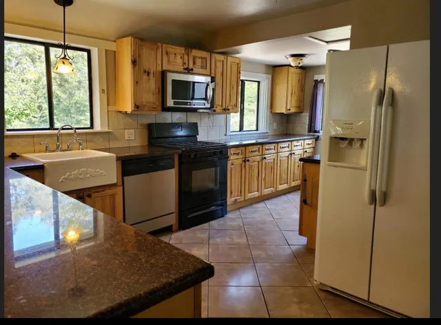 a kitchen with stainless steel appliances granite countertop a refrigerator a stove top oven a sink and dishwasher