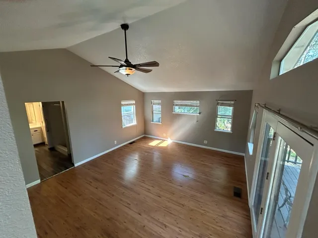a view of empty room with wooden floor and fan
