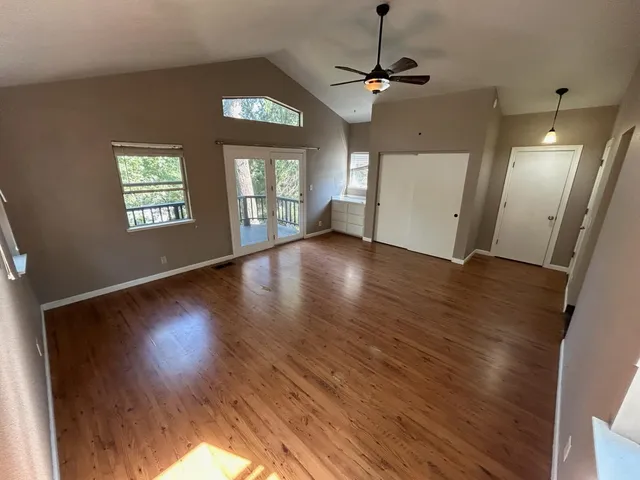 a view of an empty room with wooden floor and a window