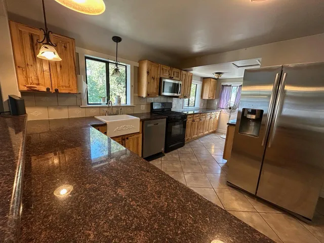 a kitchen with stainless steel appliances granite countertop a refrigerator a stove and a sink with wooden floor