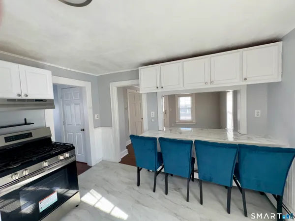 a kitchen with stainless steel appliances a stove a sink cabinets and a dining table