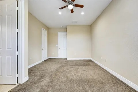 a view of an empty room with a ceiling fan and window