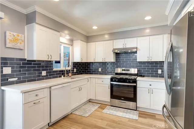 a kitchen with stainless steel appliances granite countertop a stove and white cabinets