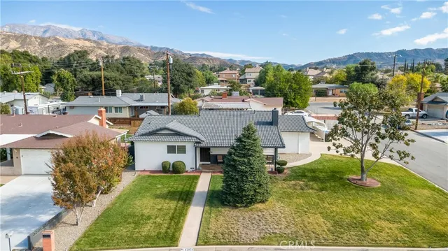 a front view of a house with a yard and mountain view