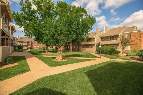 a view of a house with a big yard plants and large trees